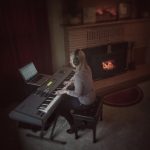 Anne working at her keyboard next to the fireplace