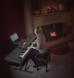 Anne working at her keyboard next to the fireplace