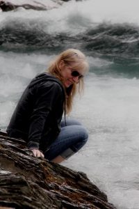 Anne sitting on the bank of a glacial creek in Jasper National Park, Alberta, Canada