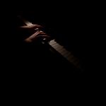 Anne's hands on the piano keys illuminated in the dark