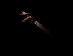 Anne's hands on the piano keys illuminated in the dark